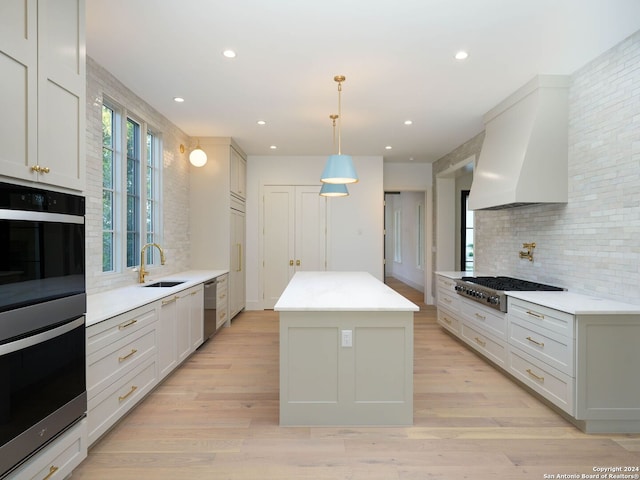 kitchen featuring stainless steel appliances, sink, a center island, pendant lighting, and custom exhaust hood