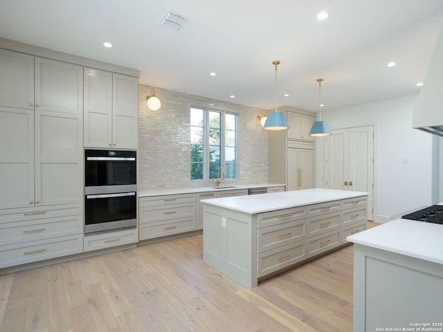 kitchen with stainless steel double oven, pendant lighting, gray cabinets, sink, and light hardwood / wood-style floors