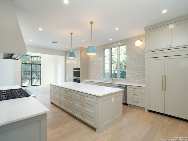 kitchen featuring a kitchen island, light hardwood / wood-style flooring, hanging light fixtures, stainless steel appliances, and sink