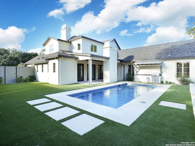 rear view of house featuring a yard, a patio area, and a fenced in pool