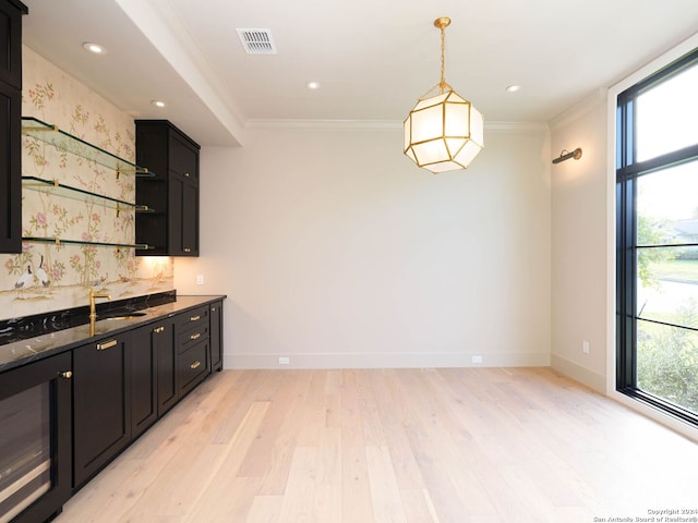 kitchen with crown molding, light hardwood / wood-style flooring, dark stone countertops, and plenty of natural light