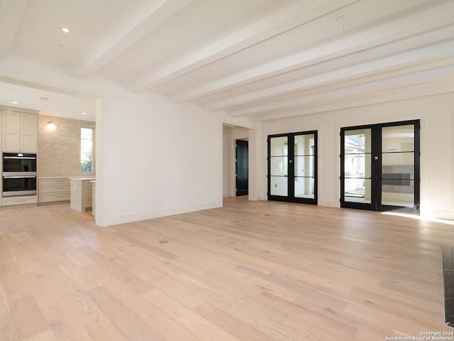 spare room with beam ceiling, french doors, and light hardwood / wood-style floors