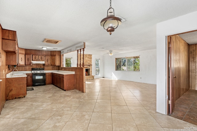 kitchen with white gas range, ceiling fan, decorative light fixtures, sink, and kitchen peninsula