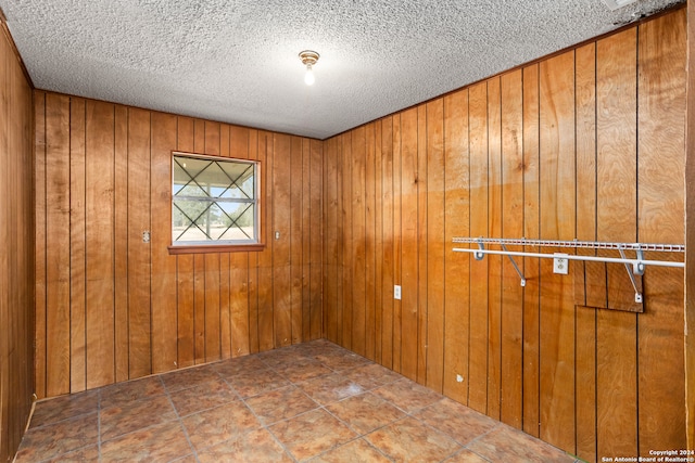 unfurnished room with wood walls and a textured ceiling