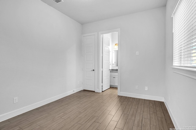 unfurnished bedroom with connected bathroom and light hardwood / wood-style flooring