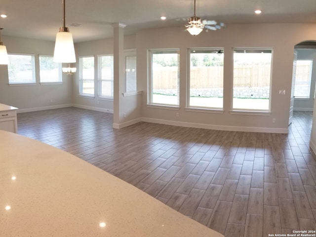 unfurnished dining area with ceiling fan, dark hardwood / wood-style floors, and a healthy amount of sunlight