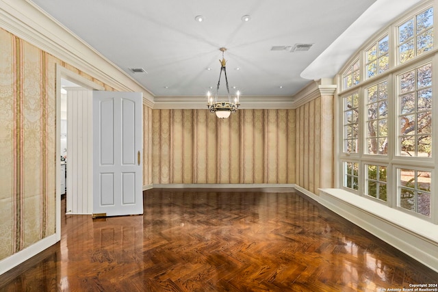 empty room with a chandelier, crown molding, and dark parquet flooring