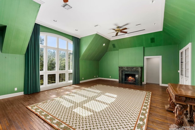 unfurnished living room featuring lofted ceiling, dark wood-type flooring, crown molding, a fireplace, and ceiling fan