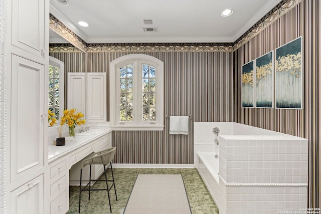 bathroom with vanity, ornamental molding, and tiled tub