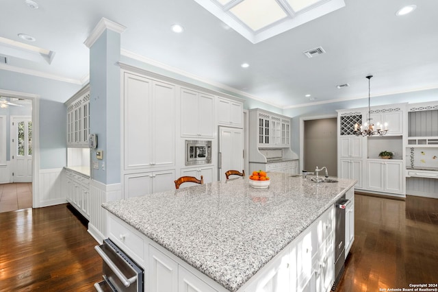 kitchen featuring dark hardwood / wood-style flooring, crown molding, white cabinets, and a large island with sink