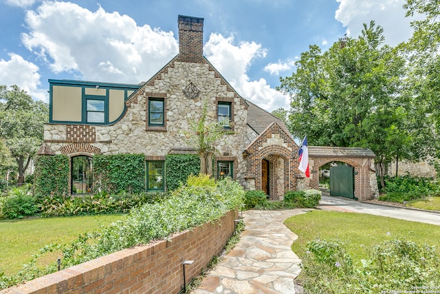 tudor house featuring a carport and a front yard