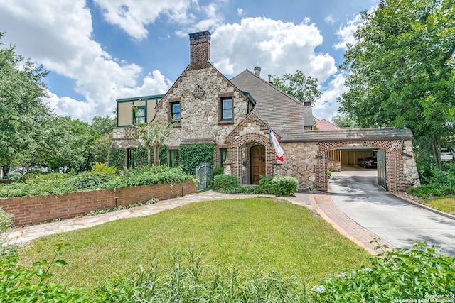 english style home featuring a carport and a front yard