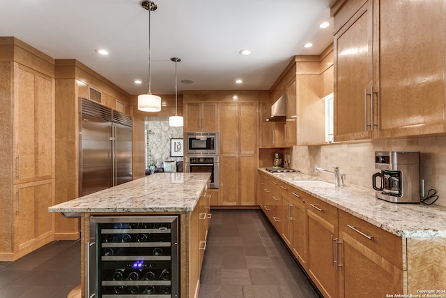 kitchen with light stone counters, beverage cooler, sink, hanging light fixtures, and built in appliances