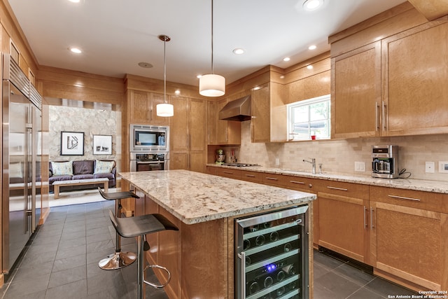 kitchen featuring wine cooler, dark tile patterned flooring, extractor fan, built in appliances, and a center island