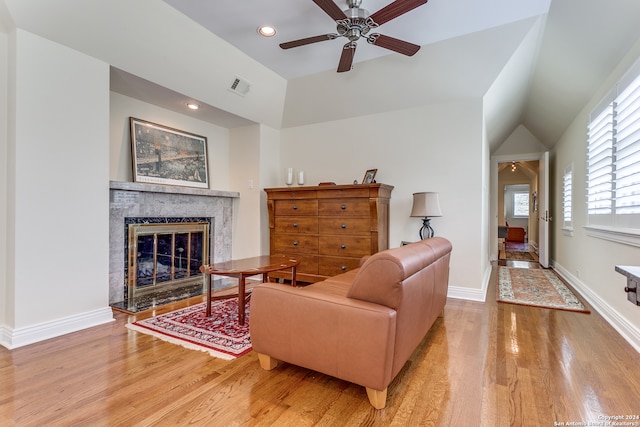 living room featuring lofted ceiling, a high end fireplace, ceiling fan, and light hardwood / wood-style flooring