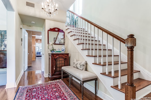 stairway with hardwood / wood-style flooring and a chandelier