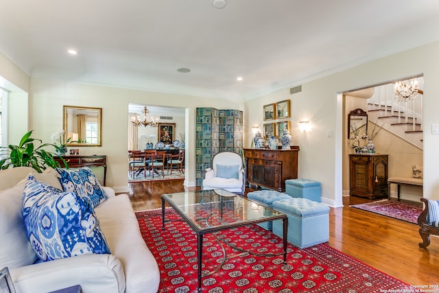 living room with wood-type flooring, ornamental molding, and a chandelier