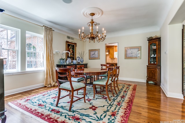 dining space with ornamental molding, hardwood / wood-style flooring, and a chandelier