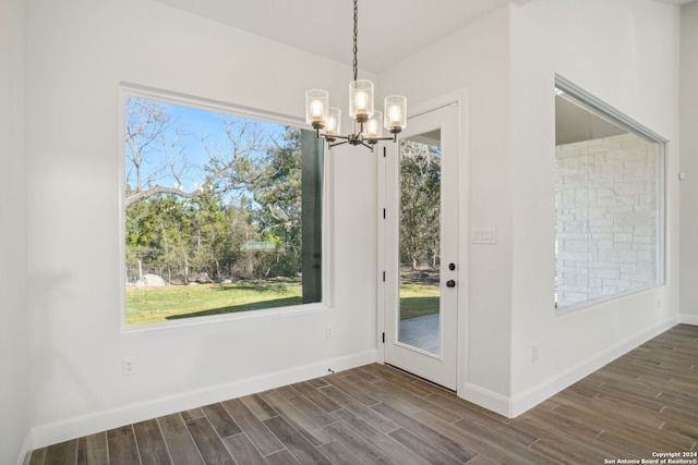 unfurnished dining area featuring a chandelier and dark wood-type flooring