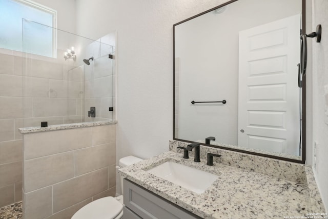 bathroom featuring toilet, vanity, and tiled shower