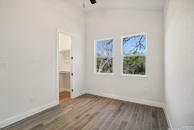 unfurnished bedroom with ceiling fan, a spacious closet, hardwood / wood-style floors, a closet, and lofted ceiling