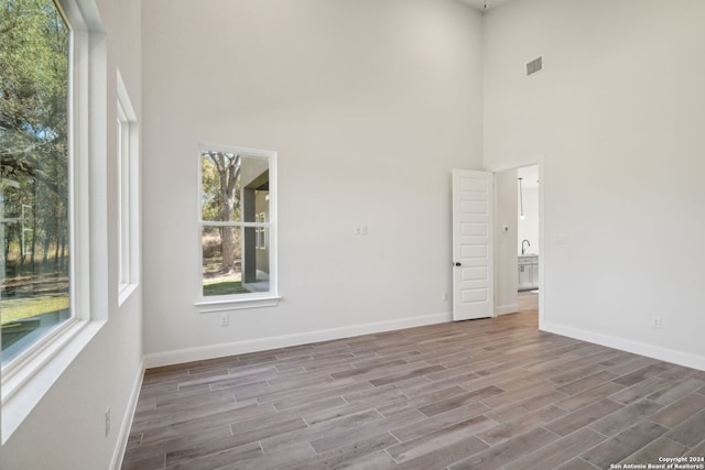 spare room featuring hardwood / wood-style flooring and a towering ceiling