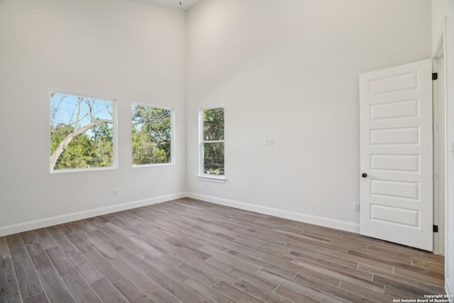 unfurnished room featuring wood-type flooring and a towering ceiling