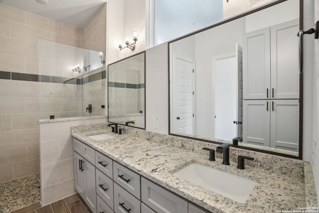 bathroom with hardwood / wood-style floors, vanity, a tile shower, and tile walls