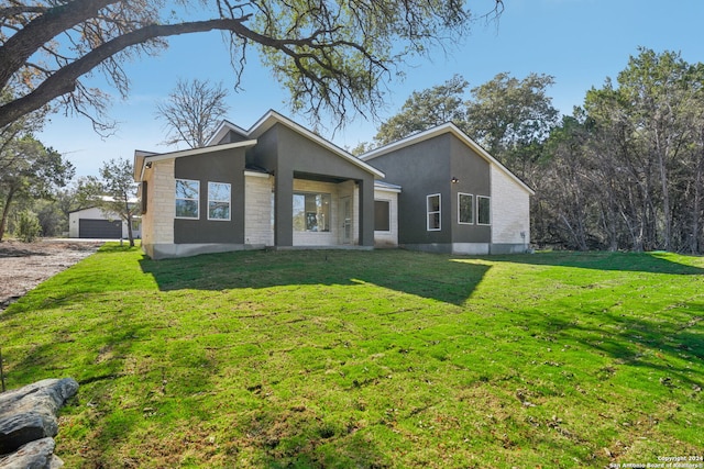 view of front facade with a front yard, a garage, and an outdoor structure