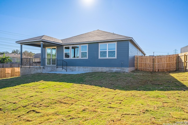 rear view of property featuring a lawn and a patio