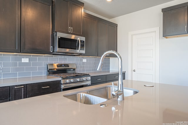 kitchen featuring dark brown cabinets, sink, stainless steel appliances, and tasteful backsplash