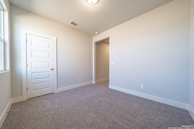 carpeted empty room featuring vaulted ceiling and a textured ceiling