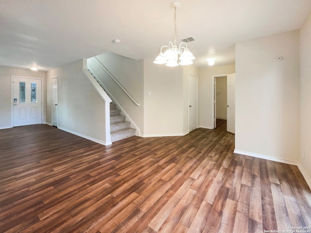 unfurnished living room featuring a notable chandelier and dark wood-type flooring