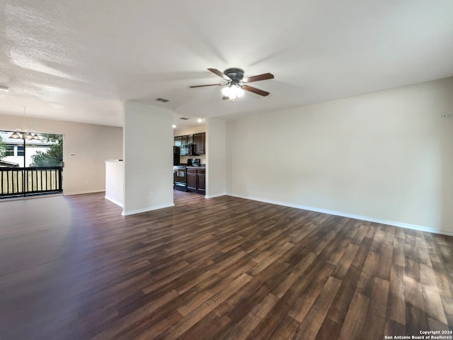 unfurnished living room featuring ceiling fan with notable chandelier and dark hardwood / wood-style flooring