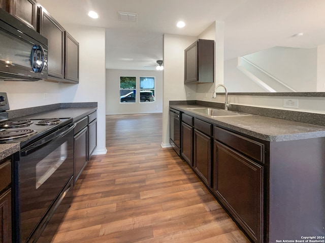 kitchen with hardwood / wood-style floors, black appliances, sink, and dark brown cabinetry