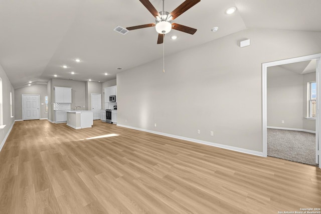 unfurnished living room with light wood-type flooring, vaulted ceiling, ceiling fan, and sink