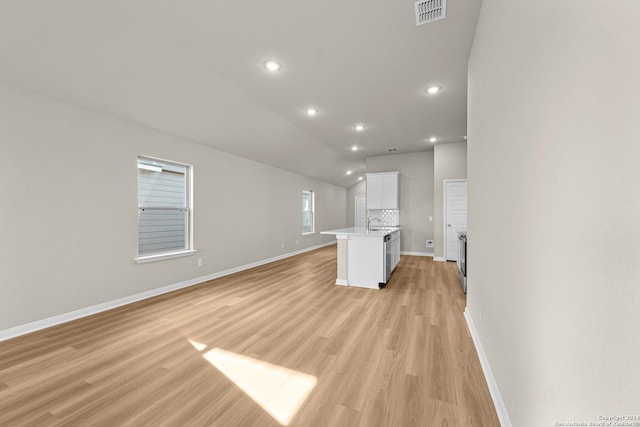 unfurnished living room featuring sink, light hardwood / wood-style floors, and vaulted ceiling