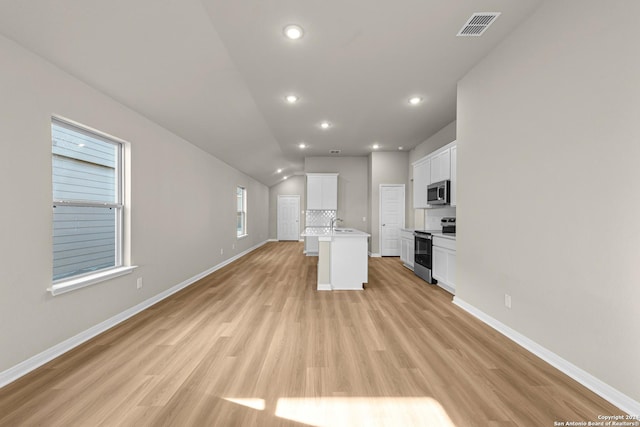 kitchen featuring lofted ceiling, a kitchen island with sink, light hardwood / wood-style flooring, appliances with stainless steel finishes, and white cabinetry