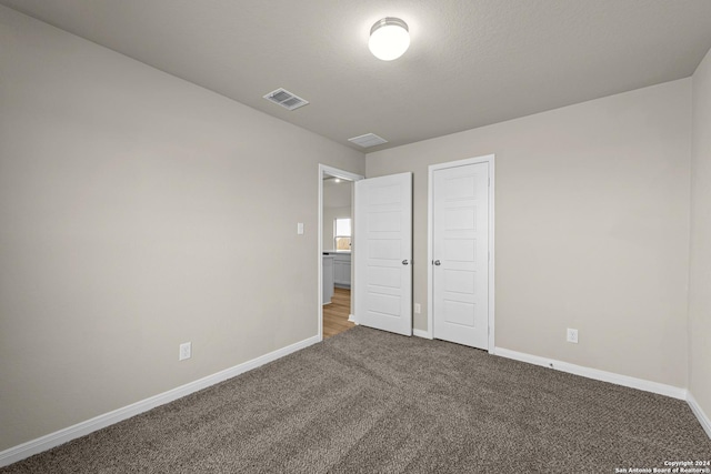 unfurnished bedroom with carpet floors, a textured ceiling, and a closet