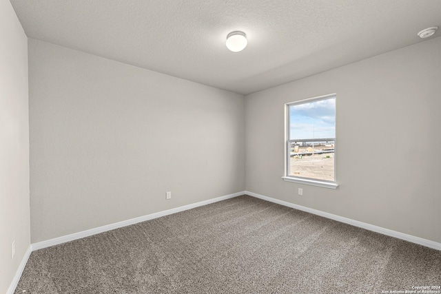 carpeted empty room featuring a textured ceiling