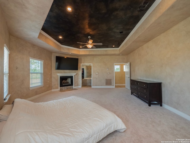 bedroom featuring a tray ceiling, light colored carpet, and ceiling fan