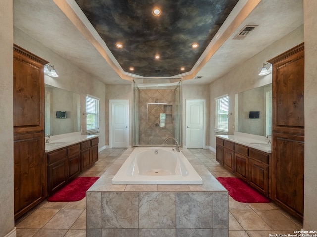 bathroom with a raised ceiling, a wealth of natural light, shower with separate bathtub, and vanity