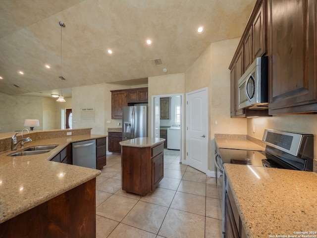 kitchen with sink, a kitchen island, decorative light fixtures, appliances with stainless steel finishes, and washer / dryer