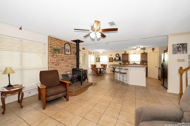 living room with light tile patterned flooring, ceiling fan, and a wood stove