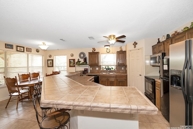 kitchen with a wealth of natural light, a breakfast bar, kitchen peninsula, and black appliances