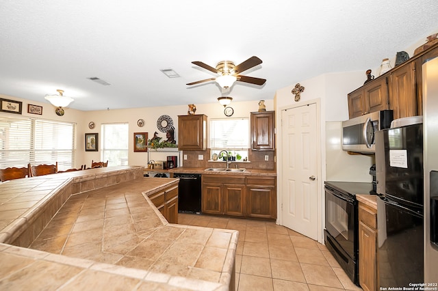 kitchen featuring light tile patterned flooring, ceiling fan, sink, tile counters, and black appliances