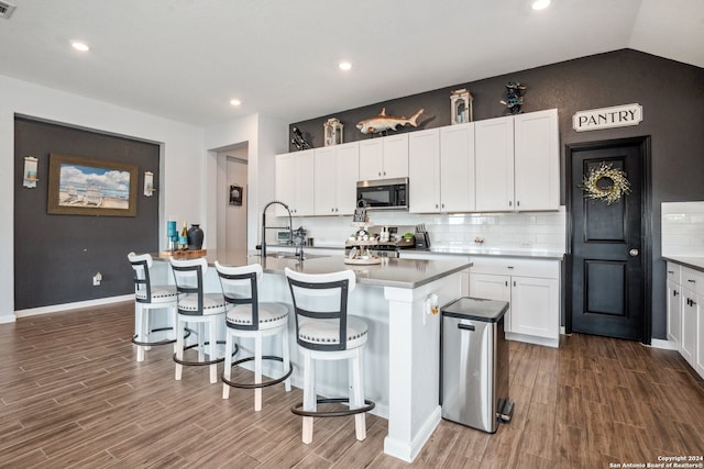 kitchen featuring dark hardwood / wood-style flooring, sink, an island with sink, appliances with stainless steel finishes, and white cabinetry