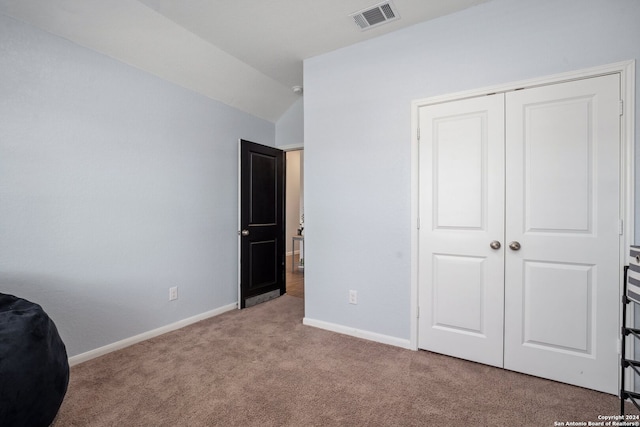 unfurnished bedroom featuring lofted ceiling, a closet, and light carpet