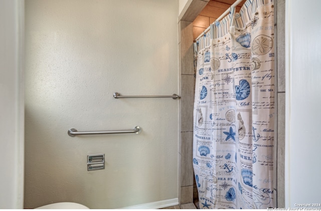 bathroom with toilet and a shower with shower curtain