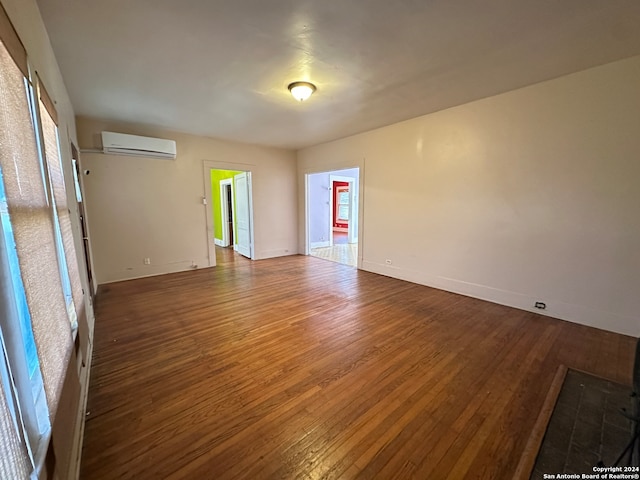 empty room with an AC wall unit and dark wood-type flooring